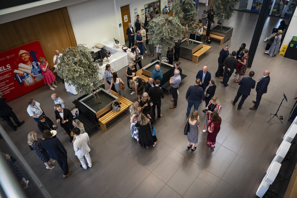 A spacious, modern interior filled with people mingling and conversing.